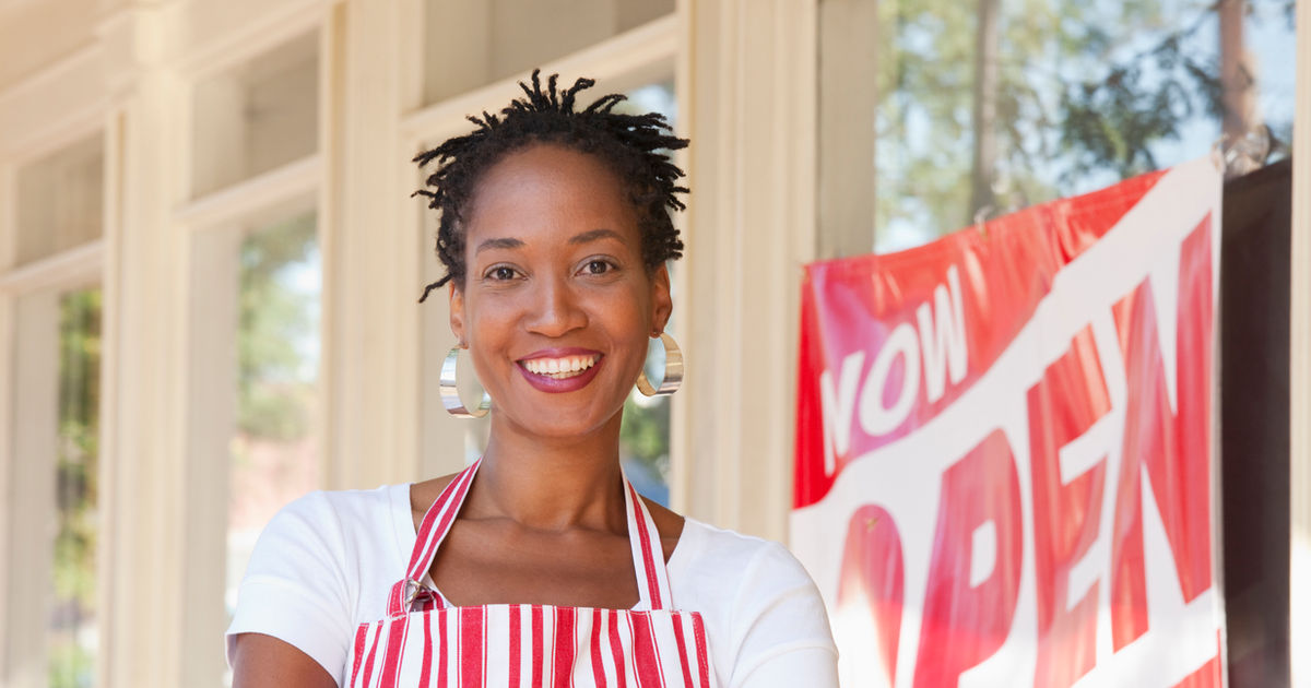 Black woman business owner with Now Open sign